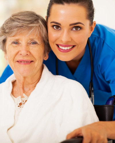 senior woman on wheelchair with nurse wearing stethoscope smiling