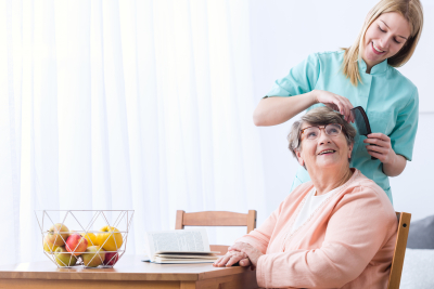 caregiver combing hair to senior woman