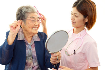 caregiver assisting senior woman taking care of her hair